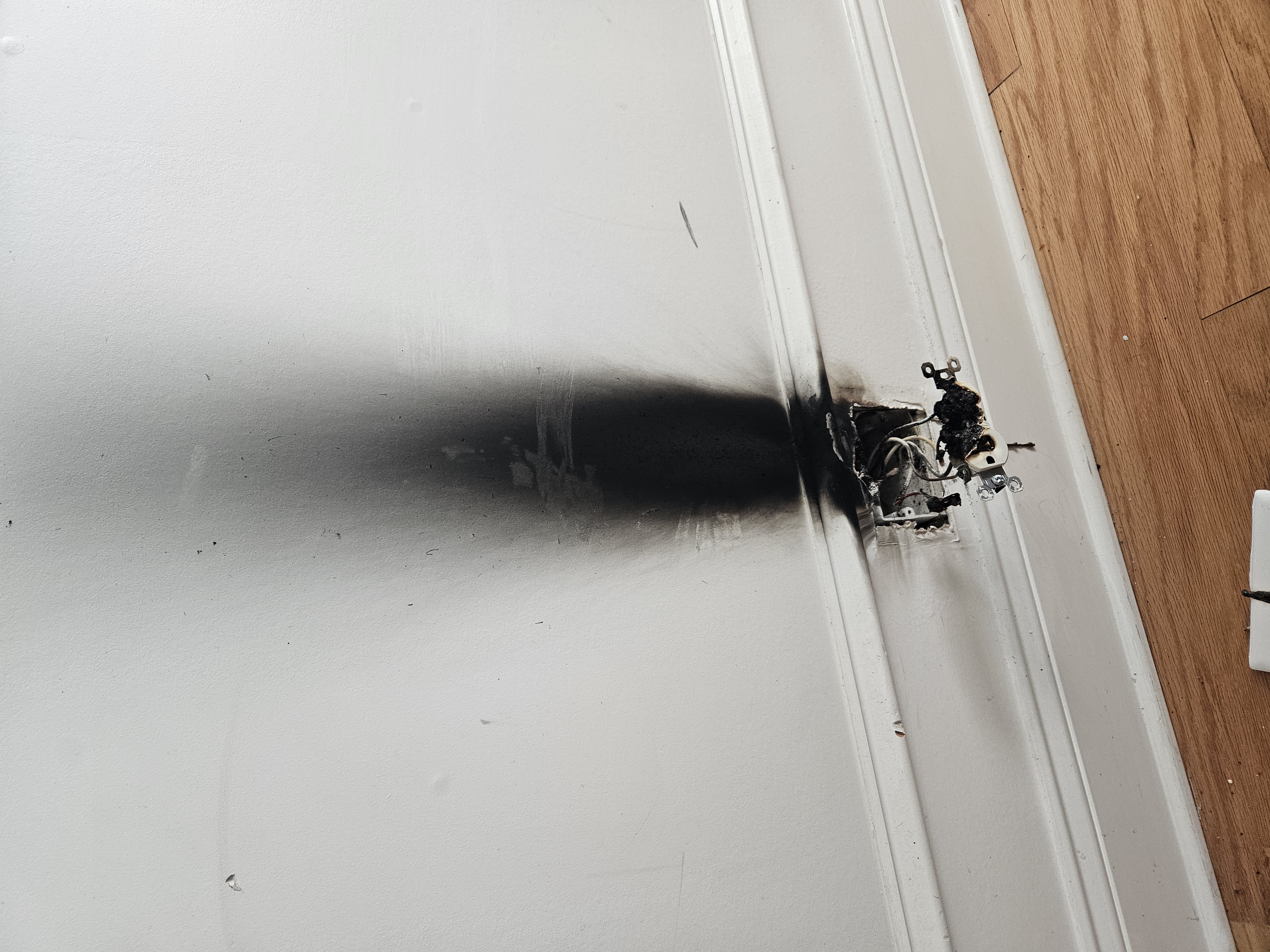 Burned and melted electrical outlet showing fire damage from faulty wiring