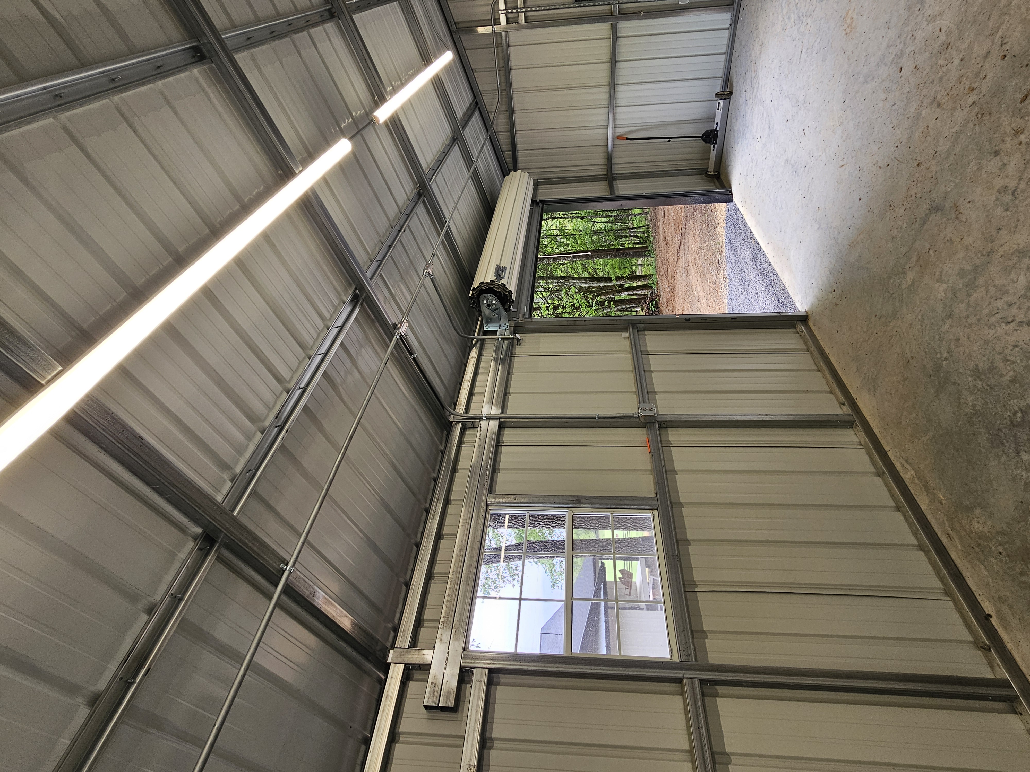 LED shop lights and electrical conduit installed in a metal garage workshop