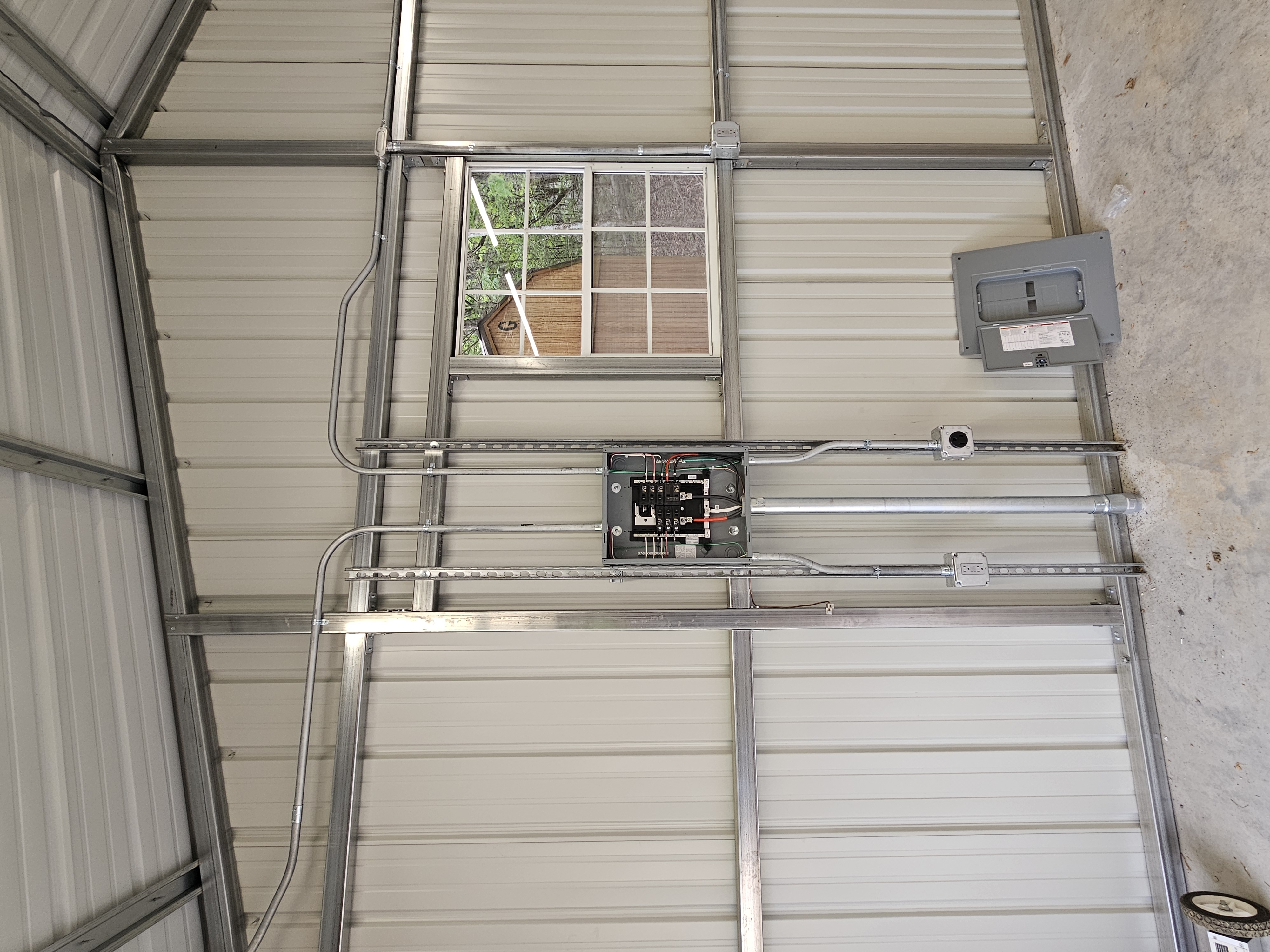 Electrical sub-panel with EMT conduit runs in a metal workshop